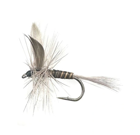 A close-up photograph showing the Blue Quill Dry Fly in sizes #14, #16, and #18. The flies feature a slim, dark gray body, slate gray wings, and dark hackle, tied on barbed hooks for an early season mayfly imitation.